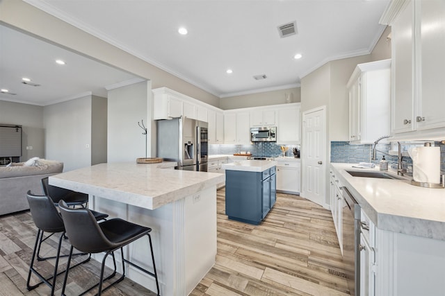 kitchen with a center island, white cabinets, light hardwood / wood-style flooring, a kitchen bar, and stainless steel appliances