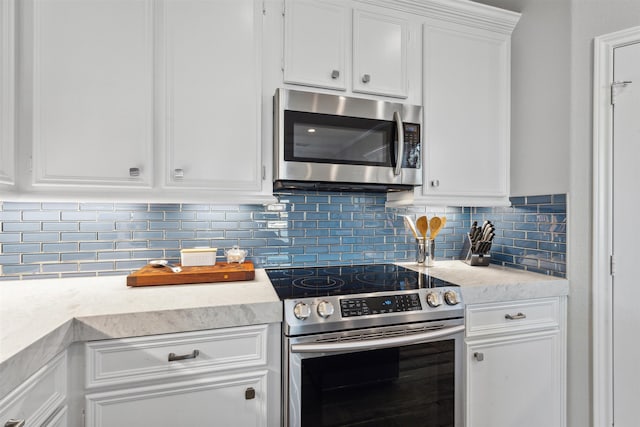 kitchen with decorative backsplash, white cabinets, and stainless steel appliances