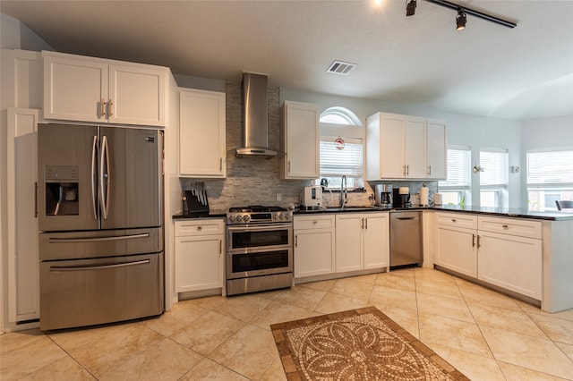 kitchen featuring appliances with stainless steel finishes, sink, a wealth of natural light, and wall chimney range hood