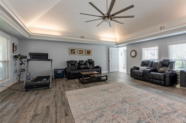 living room with hardwood / wood-style flooring, ceiling fan, crown molding, and a tray ceiling