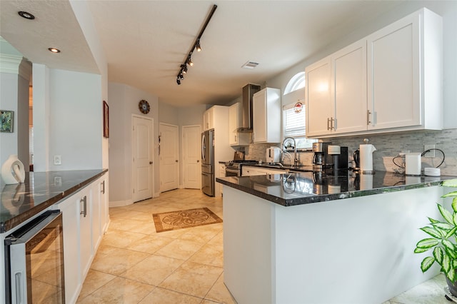 kitchen featuring stainless steel refrigerator, white cabinetry, sink, wall chimney range hood, and wine cooler