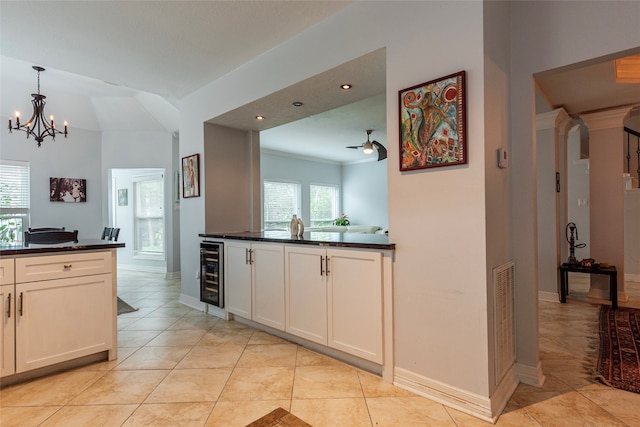 kitchen with ceiling fan with notable chandelier, light tile patterned floors, white cabinetry, and beverage cooler