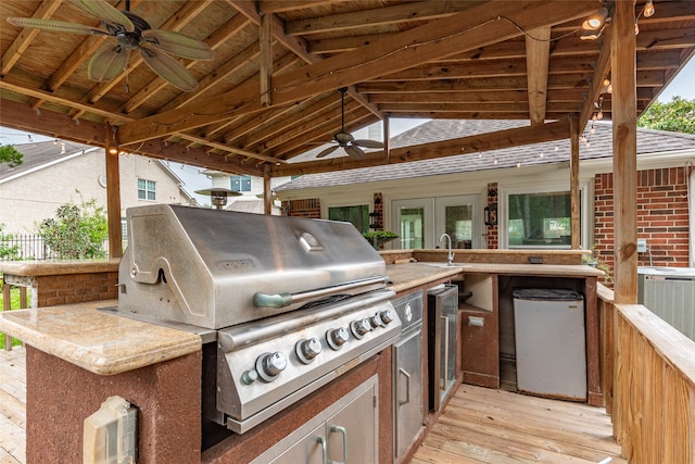 view of patio with area for grilling, a deck, ceiling fan, grilling area, and an outdoor bar