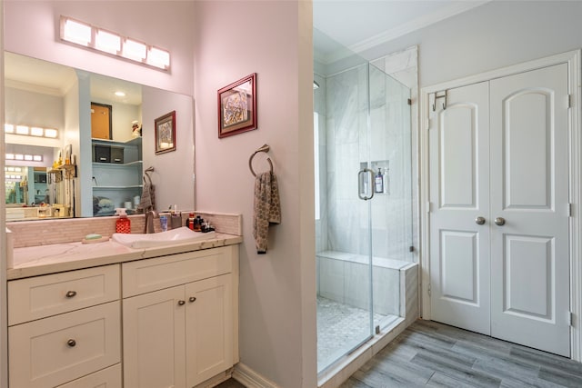 bathroom with hardwood / wood-style flooring, a shower with door, vanity, and ornamental molding