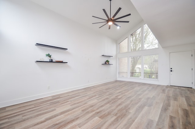 unfurnished living room featuring a wealth of natural light, light wood-type flooring, and high vaulted ceiling