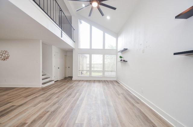 unfurnished living room featuring a towering ceiling, light hardwood / wood-style floors, and a healthy amount of sunlight