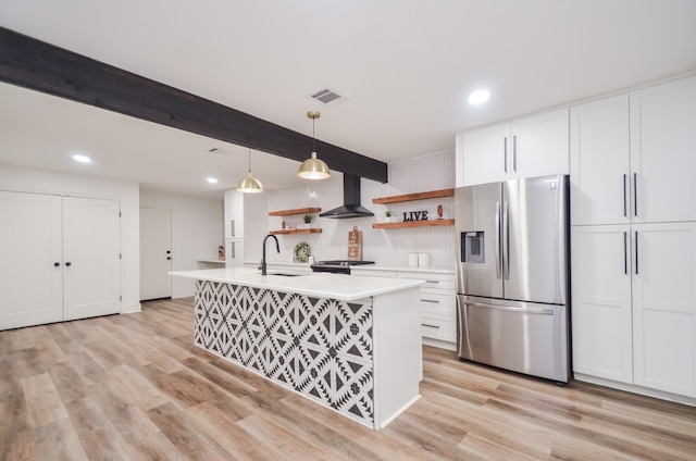 kitchen with stainless steel appliances, sink, wall chimney range hood, white cabinetry, and hanging light fixtures