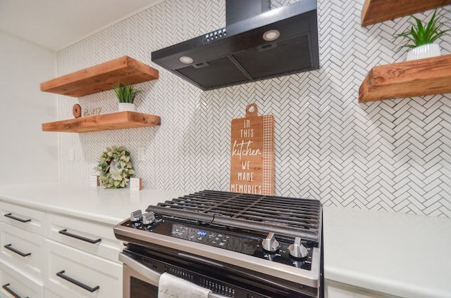 kitchen featuring wall chimney range hood, white cabinets, and stainless steel range oven