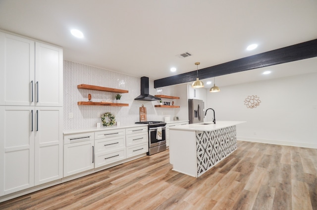 kitchen with white cabinets, wall chimney range hood, hanging light fixtures, light wood-type flooring, and stainless steel appliances