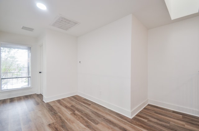 spare room with dark wood-type flooring and a skylight