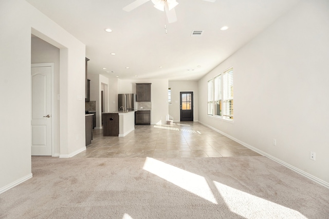 unfurnished living room featuring ceiling fan and light colored carpet