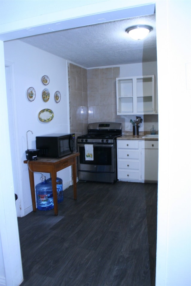 kitchen with dark hardwood / wood-style flooring, stainless steel gas range oven, a textured ceiling, sink, and white cabinetry