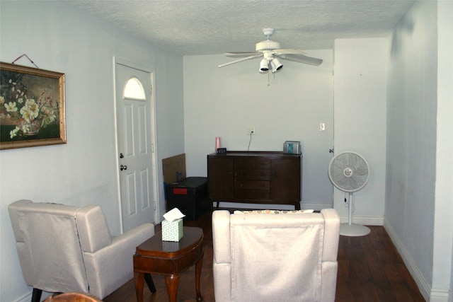 living area featuring a textured ceiling, dark hardwood / wood-style floors, and ceiling fan