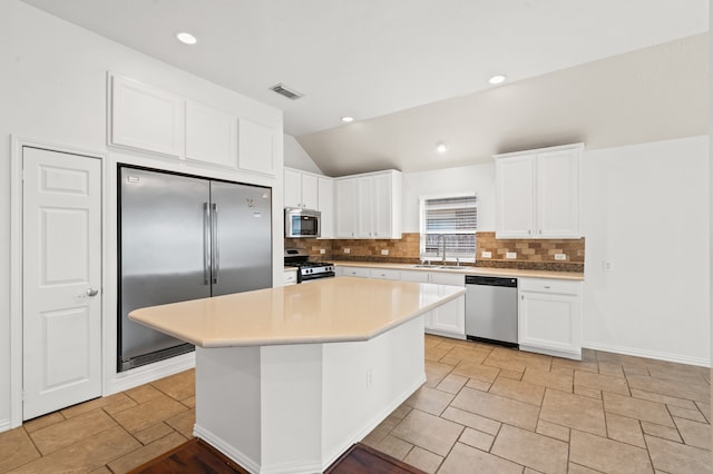 kitchen featuring appliances with stainless steel finishes, sink, white cabinets, a kitchen island, and lofted ceiling