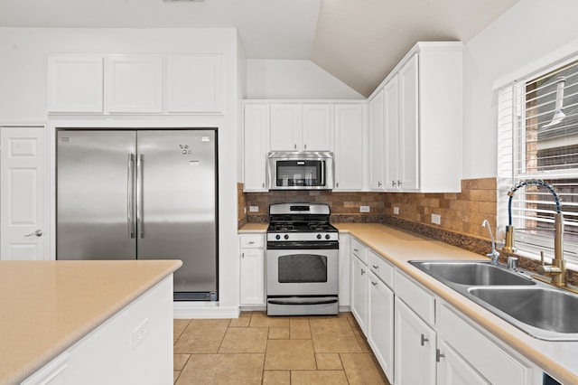 kitchen featuring white cabinetry, sink, tasteful backsplash, lofted ceiling, and appliances with stainless steel finishes