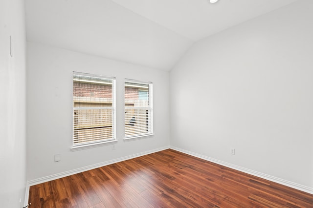 spare room featuring dark wood-type flooring and vaulted ceiling