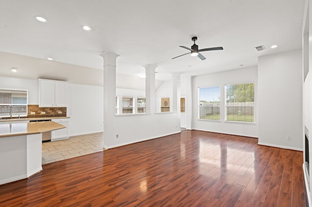 unfurnished living room with ornate columns, ceiling fan, light hardwood / wood-style flooring, and sink