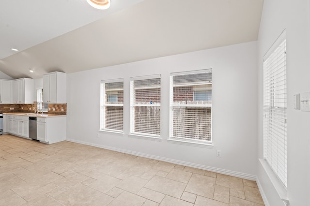 kitchen featuring sink, tasteful backsplash, stainless steel dishwasher, lofted ceiling, and white cabinets