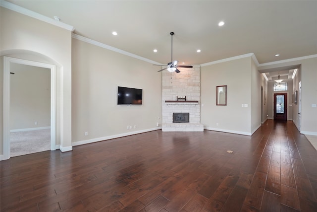 unfurnished living room with dark hardwood / wood-style floors, a stone fireplace, ceiling fan, and ornamental molding