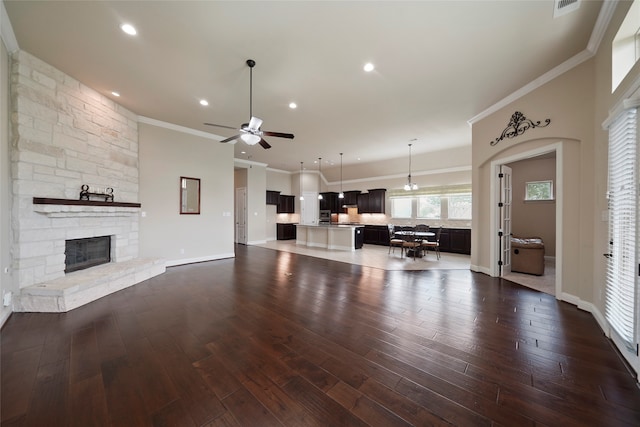 unfurnished living room featuring ceiling fan, crown molding, and dark wood-type flooring