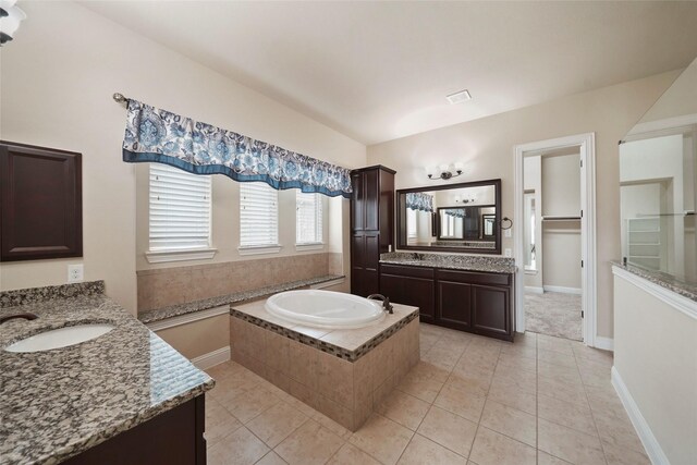 bathroom with tile patterned flooring, vanity, and tiled tub