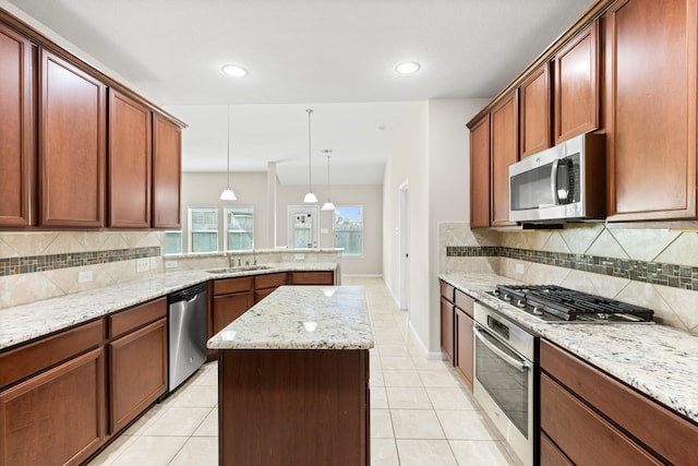 kitchen with light stone counters, stainless steel appliances, hanging light fixtures, and tasteful backsplash