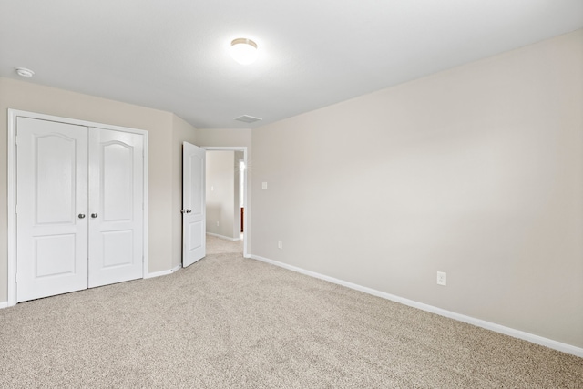 unfurnished bedroom with light colored carpet and a closet