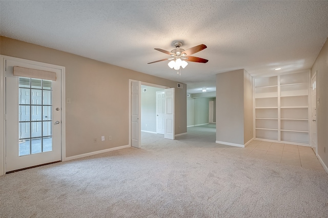 empty room featuring a textured ceiling, light colored carpet, and ceiling fan