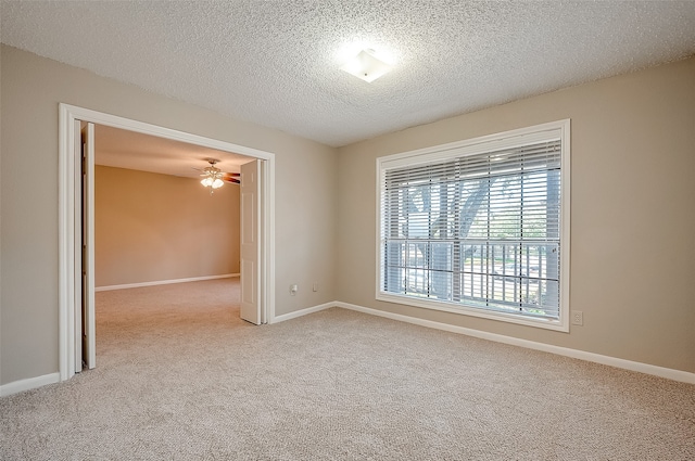 empty room with light carpet, a textured ceiling, and ceiling fan