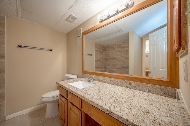 bathroom with tile patterned floors, vanity, a textured ceiling, and toilet