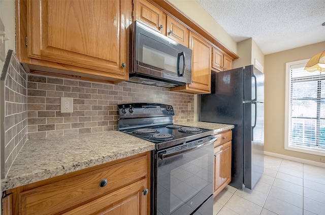 kitchen with tasteful backsplash, light tile patterned flooring, black appliances, and a textured ceiling