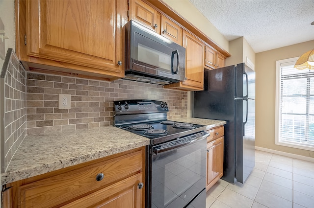 kitchen featuring tasteful backsplash, light tile patterned flooring, black appliances, and a textured ceiling