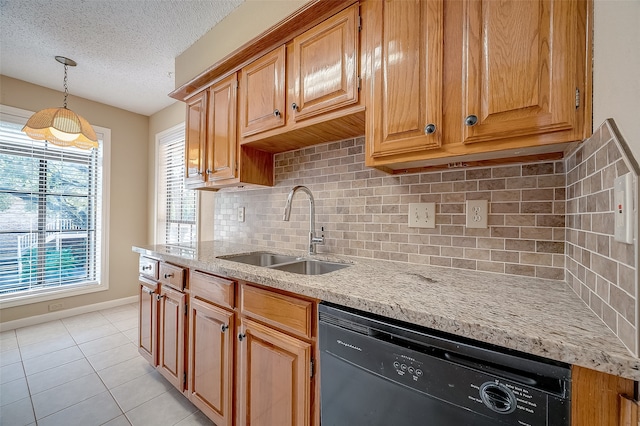 kitchen featuring sink, black dishwasher, tasteful backsplash, decorative light fixtures, and light stone counters