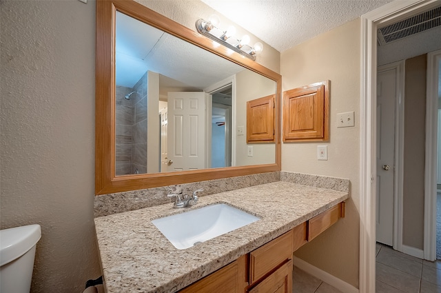 bathroom featuring tile patterned flooring, a shower, a textured ceiling, toilet, and vanity