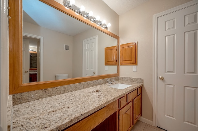 bathroom with tile patterned floors, vanity, toilet, and a textured ceiling