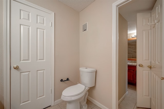 bathroom with tile patterned flooring, vanity, a textured ceiling, and toilet