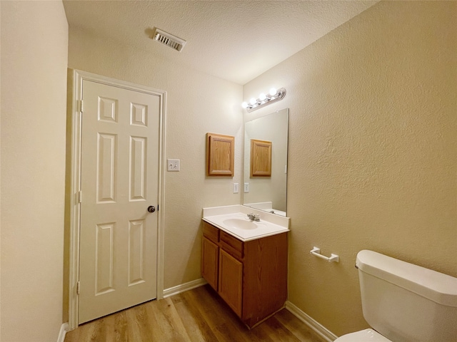 bathroom featuring toilet, vanity, a textured ceiling, and hardwood / wood-style floors