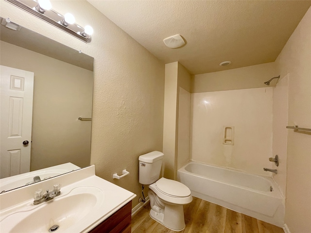 full bathroom with toilet, wood-type flooring, vanity, bathing tub / shower combination, and a textured ceiling