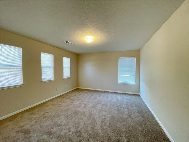 unfurnished room with a textured ceiling and carpet