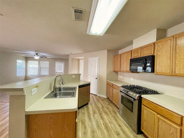 kitchen featuring light hardwood / wood-style floors, a kitchen island with sink, appliances with stainless steel finishes, ceiling fan, and sink