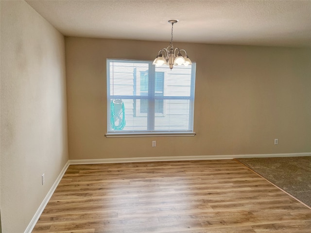 unfurnished room featuring wood-type flooring, a chandelier, and a wealth of natural light