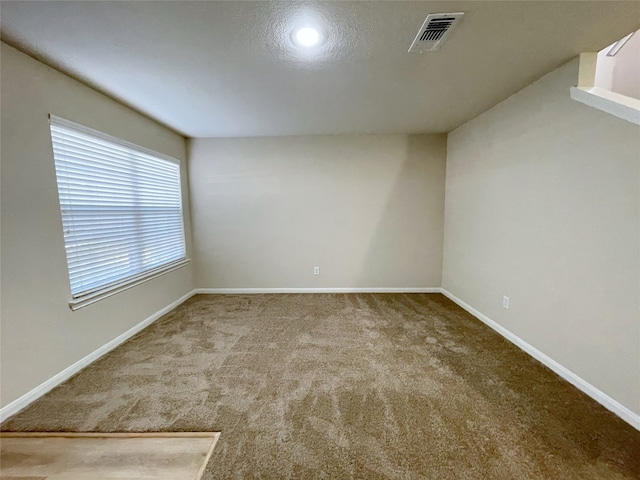 carpeted empty room with a textured ceiling