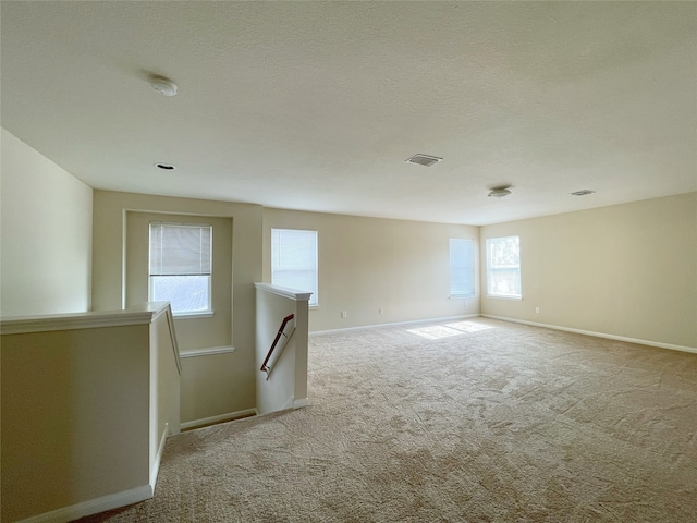 empty room featuring a textured ceiling and light carpet