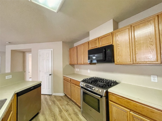 kitchen with appliances with stainless steel finishes and light hardwood / wood-style floors