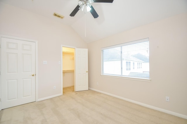 unfurnished bedroom with light carpet, ceiling fan, a spacious closet, a closet, and lofted ceiling