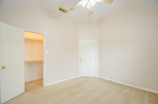 unfurnished bedroom with light carpet, a spacious closet, ceiling fan, and lofted ceiling