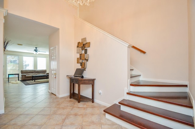 staircase featuring tile patterned flooring and ceiling fan with notable chandelier