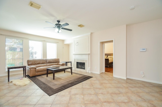 tiled living room with ceiling fan and a fireplace