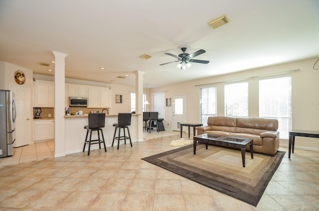 tiled living room featuring decorative columns and ceiling fan