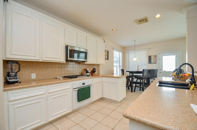 kitchen with sink, hanging light fixtures, tasteful backsplash, white cabinetry, and stainless steel appliances